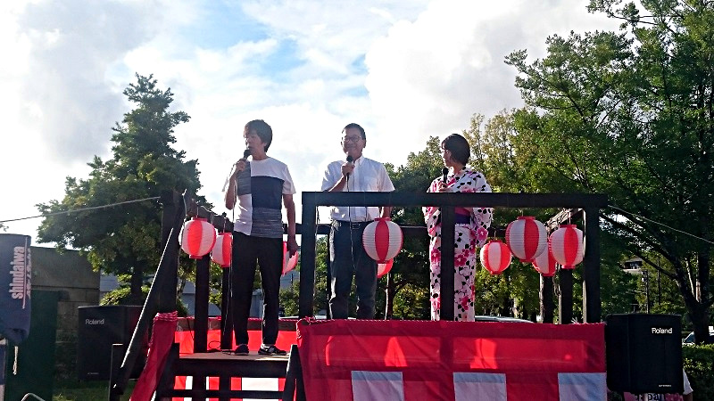 フライデーナイトJリーグ「祭りやぐら」イベントにてヤグラの上に立つ高田社長、村井チェアマン、サトミキの3ショット